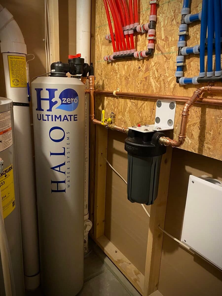 Water filtration system installation showing a tall cylindrical filter tank with copper piping